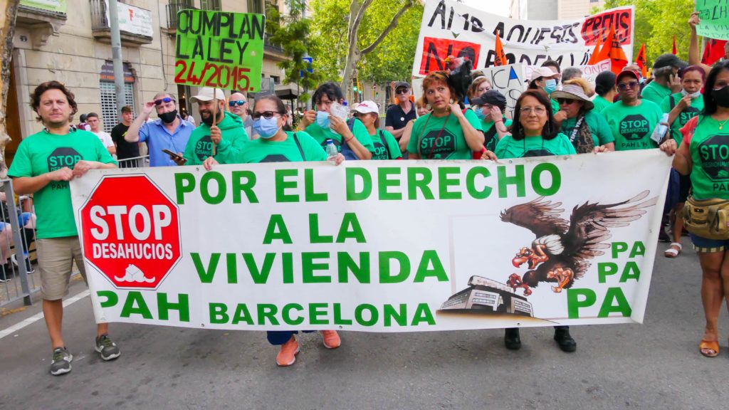 Activistes de la PAH carrguen una pancarta on es llegeix "Por el derecho a la vivienda" mentre desfilen pels centre de Barcelona